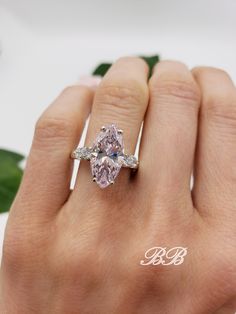 a woman's hand holding a pink diamond ring