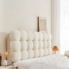 the headboard of a bed in a bedroom with white sheets and pillows on it