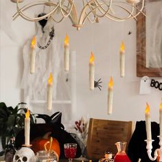 a dining room table with candles hanging from it's ceiling and halloween decorations on the wall