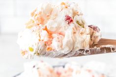 a spoon full of food sitting on top of a cake plate with white frosting and cranberries