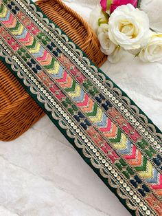 a woven piece of cloth next to a wicker basket with flowers in the background