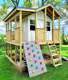 there is a small tree house with a slide on the grass in front of it