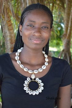 a woman wearing a black shirt and white necklace with shells on it's neck