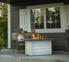 two women sitting around a fire pit on the front steps of a house, talking