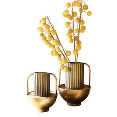 two metal vases with yellow flowers in them