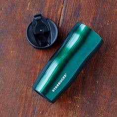 a green cup sitting on top of a wooden table next to a black canister