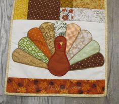 a close up of a turkey quilt on a wooden surface