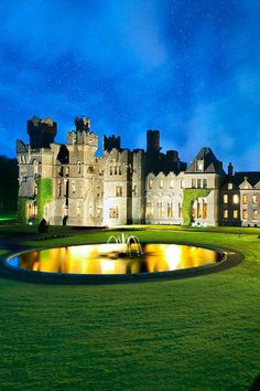 a castle lit up at night with water fountain