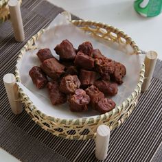 a bowl filled with meat sitting on top of a table next to a wooden stick