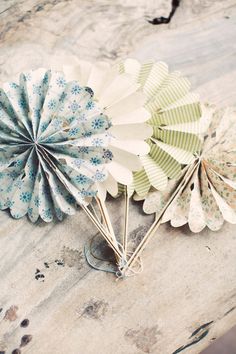 two paper fans sitting on top of a wooden table