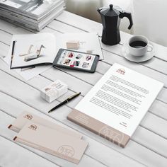 an assortment of stationery items on a table with a cup of coffee and tablet