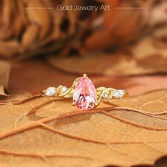 a pink ring sitting on top of a leaf covered ground