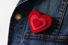 a red felt heart in the pocket of a jean jacket