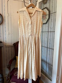 This gorgeous dress is made from cotton eyelet in creamy light beige. It fastens with buttons in the front. The measurements, taken with the dress lying flat, are: shoulder to shoulder,14 inches; armpit to armpit, 18 inches; waist, 13 inches; length, 42 inches; bottom edge, 40+ inches. In very good condition. Sleeveless Eyelet Dress For Spring, White Vintage Sleeveless Dress For Summer, Vintage White Sleeveless Dress For Summer, White Vintage Sleeveless Summer Dress, Summer Wedding Dress With Eyelet Details, White Broderie Anglaise Sleeveless Maxi Dress, White Sleeveless Broderie Anglaise Maxi Dress, White Sleeveless Maxi Dress With Broderie Anglaise, Fitted Cream Dress With Broderie Anglaise