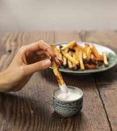 a person is dipping some fries into a small bowl