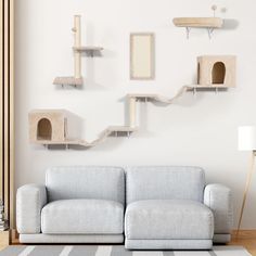 a living room with a couch, cat tree and shelves on the wall above it