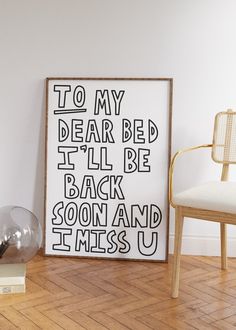 a black and white poster sitting on top of a wooden floor next to a chair