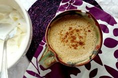 there is a cup of coffee next to a bowl of whipped cream on the table