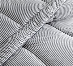 a close up view of a bed with blue and white striped sheets