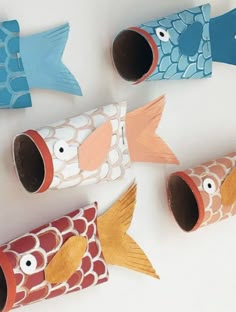 four fish made out of toilet paper sitting on top of a white table next to each other