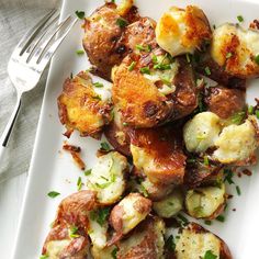 a white plate topped with potatoes covered in sauce and garnished with parsley