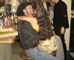 a man and woman hug each other in front of a table full of people at a party