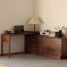 a room with a desk, lamp and rug on the floor in front of it