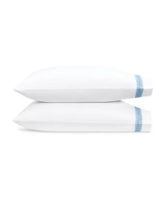 two white pillows sitting next to each other on top of a pillow case with blue trim