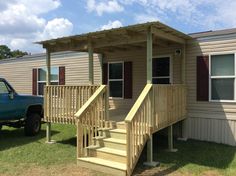 a truck parked next to a mobile home with stairs leading up to the front door