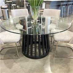 a glass table with chairs around it and a vase filled with flowers on the top