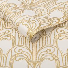 a white and gold wallpaper with an intricate design on it's side, next to a roll of toilet paper