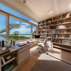 a home office with a large window overlooking the ocean and trees on the other side