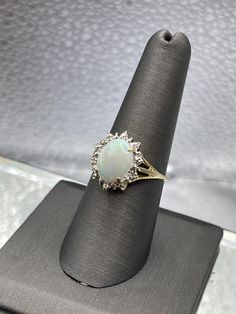 A ladies beautifully designed 14 karat solid yellow gold ring with a large oval shaped Opal accented with a halo of diamonds.   Weight:  2.9 grams Size:  8 Please See Our Video Remember - If you're purchasing for yourself or a gift for a loved one, buy with confidence.  We Guarantee Everything We Sell!  SKU #R961 Gold Oval Cabochon Diamond Ring For Formal Occasions, Gold Diamond Ring Oval Cabochon For Formal Occasions, Formal Gold Diamond Ring With Oval Cabochon, Oval Halo Diamond Ring For Formal Occasions, White Oval Cluster Ring For Anniversary, Oval Diamond Halo Ring For Formal Occasions, Formal Oval Diamond Ring With Halo Design, Exquisite Oval Halo Ring For Formal Occasions, Elegant Diamond Halo Ring