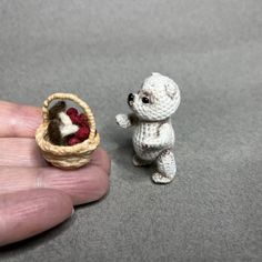 a tiny white teddy bear next to a miniature basket with raspberries