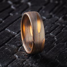 * Price may vary depending on ring size, please inquire with us directly with your needed size for accurate pricing! This beautiful but rugged feeling mokume gane ring features Arn's signature Flow pattern with solid knots, an etched and oxidized finish and a low dome profile. This ring is shown in the Fire metal combination of 14k red gold, 14kt yellow gold and oxidized sterling silver. The pattern is effortless yet intricate, evoking the movements of nature our Flow pattern is inspired by. The solid knots create pools of gold around which the other layers of metal wind like a shining river.  Style: Band  Size Shown: 10.75  Palette: Fire Pattern: Flow with Solid Knots Width: 5mm Finish: Etched & Oxidized Profile: Low Dome *Price does NOT include stones and setting fees* All Arn Krebs Moku Rustic Wedding Band, Mokume Gane Ring, Rustic Wedding Bands, Mokume Gane, Oxidized Sterling Silver, Gold Style, The Fire, Silver Band, Red Gold