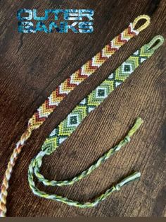 two braided bracelets sitting on top of a wooden table