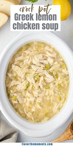 a white bowl filled with chicken soup next to sliced bread and lemons on the side