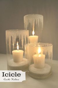 three lit candles in glass containers with icicles on them