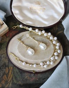 a pearl necklace and earring set in a velvet case on a cloth covered table