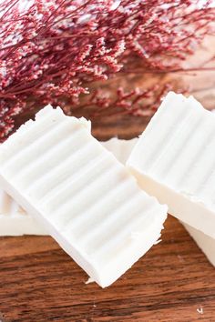 two pieces of white soap sitting on top of a wooden table