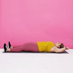 a woman is laying on her stomach in a yoga pose against a bright pink wall