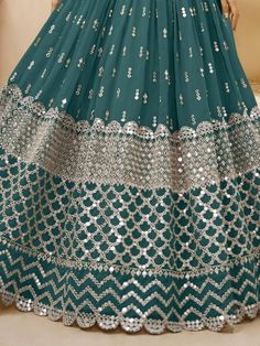 Dress up in traditional and ethnic attire like a true style icon with our spectacular teal blue zari work georgette wedding wear lehenga choli. This trendy lehenga set is perfect for any wedding or bridesmaid occasion, adding elegance and charm to your look.
The lehenga features a beautiful teal blue color with exquisite zari embroidery and heavy sequin work. Made from high-quality georgette material, it is designed to provide comfort and a stunning silhouette. The choli, in a matching teal blue Teal Blue Lehenga, Stylish Lehenga, Bridesmaid Dresses Indian, Embroidery Lehenga, Georgette Material, Sabyasachi Lehenga, Zari Embroidery, Blue Lehenga, Lehenga Style