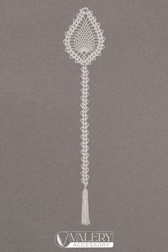 a white crocheted tassel hanging from the side of a wall next to a clock