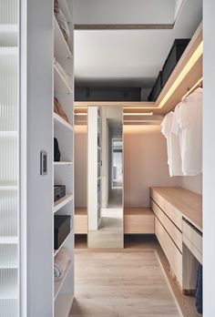 a walk in closet with white walls and wooden flooring, built into the ceiling