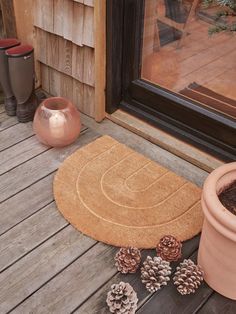 a door mat sitting on top of a wooden floor next to potted pine cones