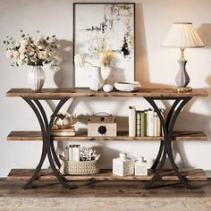 a wooden table topped with two shelves filled with books and vases next to a lamp