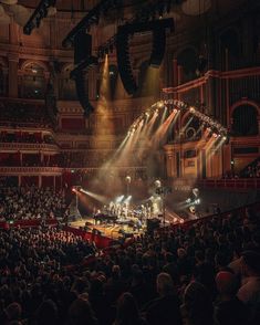 an auditorium filled with lots of people and lights on the stage in front of them