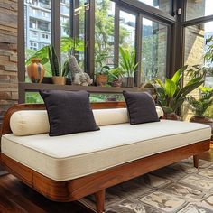 a couch sitting in front of a window with lots of plants on top of it