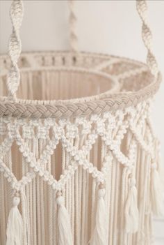 a crocheted basket with tassels hanging from it