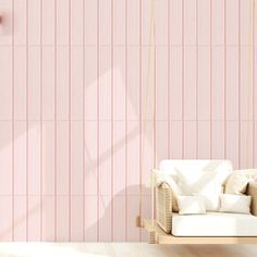 a white couch sitting in front of a pink wall with vertical lines on the wall